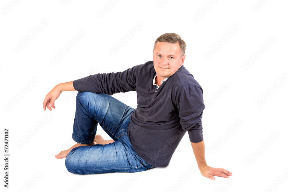 Casually dressed middle aged man sitting on a floor barefoot Casually dressed middle aged man sitting on a floor barefoot