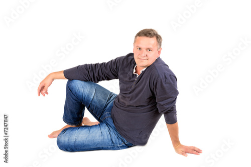 Casually dressed middle aged man sitting on a floor barefoot