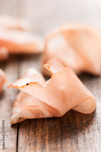 Cured ham on wooden background macro vertical