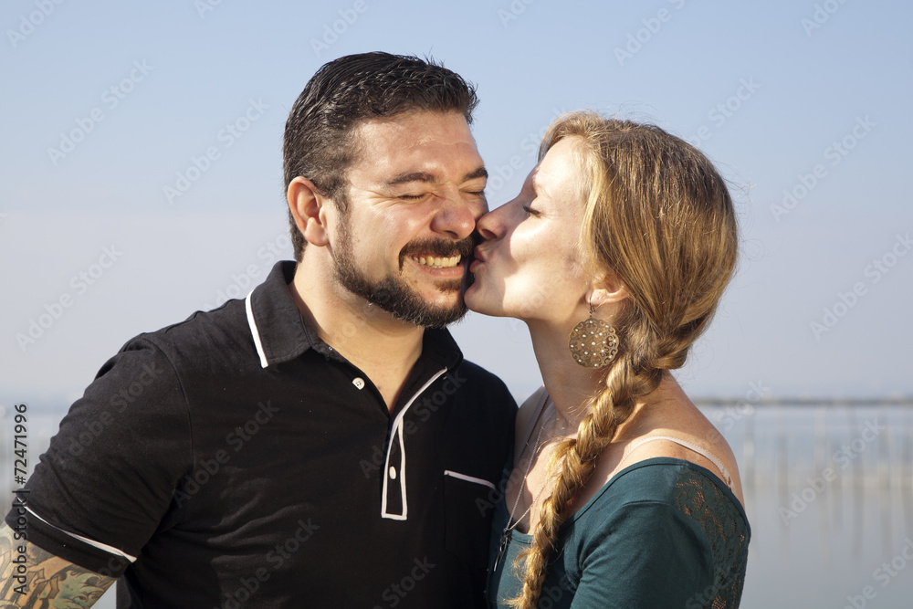 Mujer rubia con trenza besando a hombre con barba Mujer rubia con trenza besando a hombre con barba