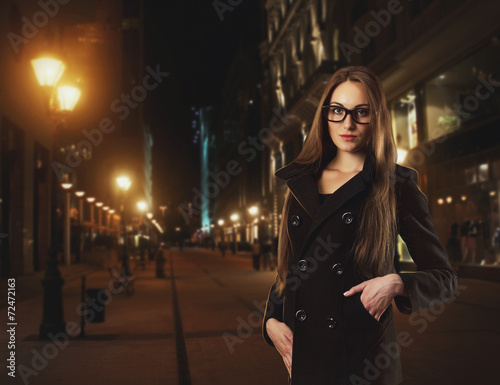 Beautiful young woman against a city by night