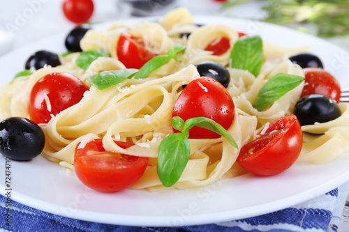 Spaghetti with tomatoes, olives and basil leaves