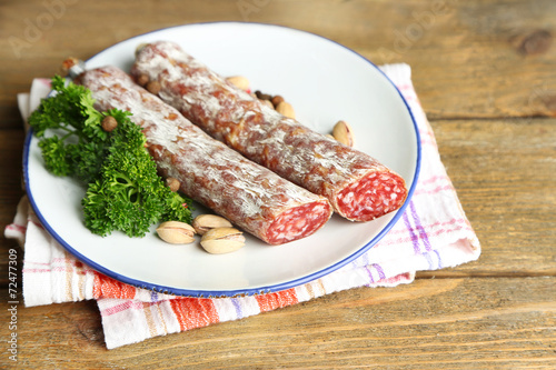 Italian salami on plate, on wooden background