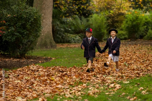 Brother and sister walking hand-in-hand through leaves