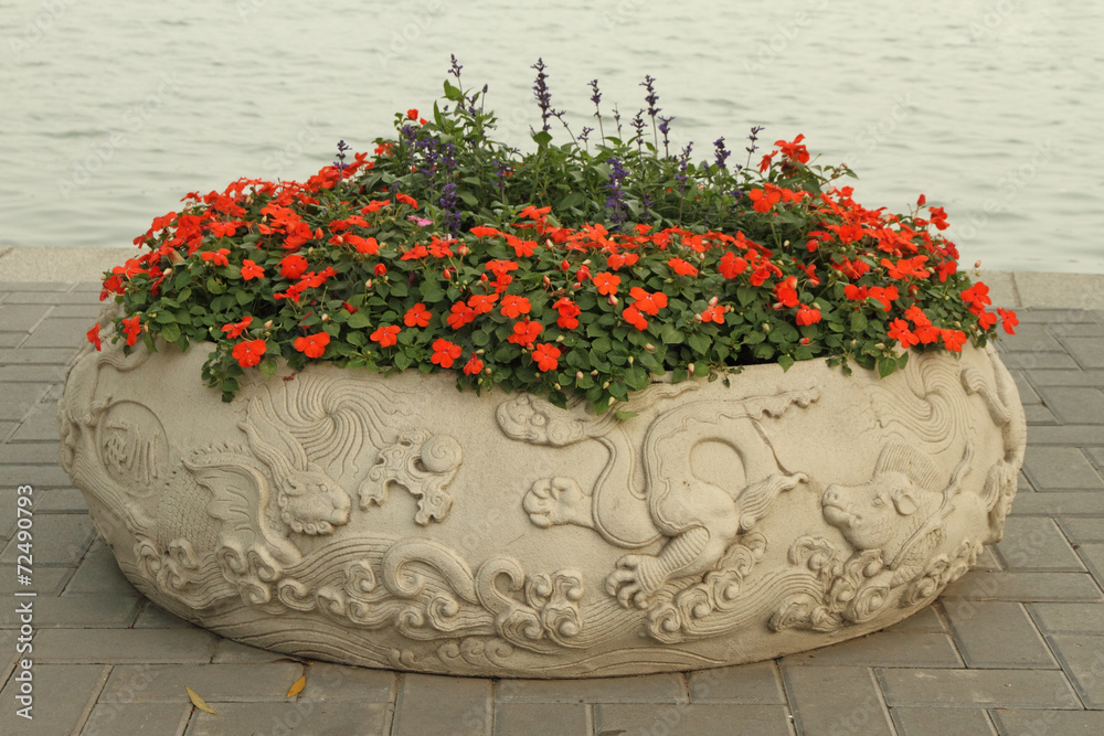 bowl  decorated with dragon reliefs and red impatiens flowers on