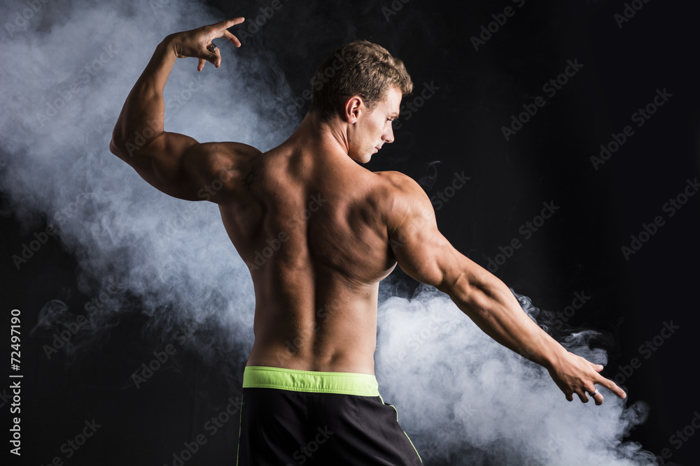 Obraz premium Handsome shirtless bodybuilder striking a pose, back view