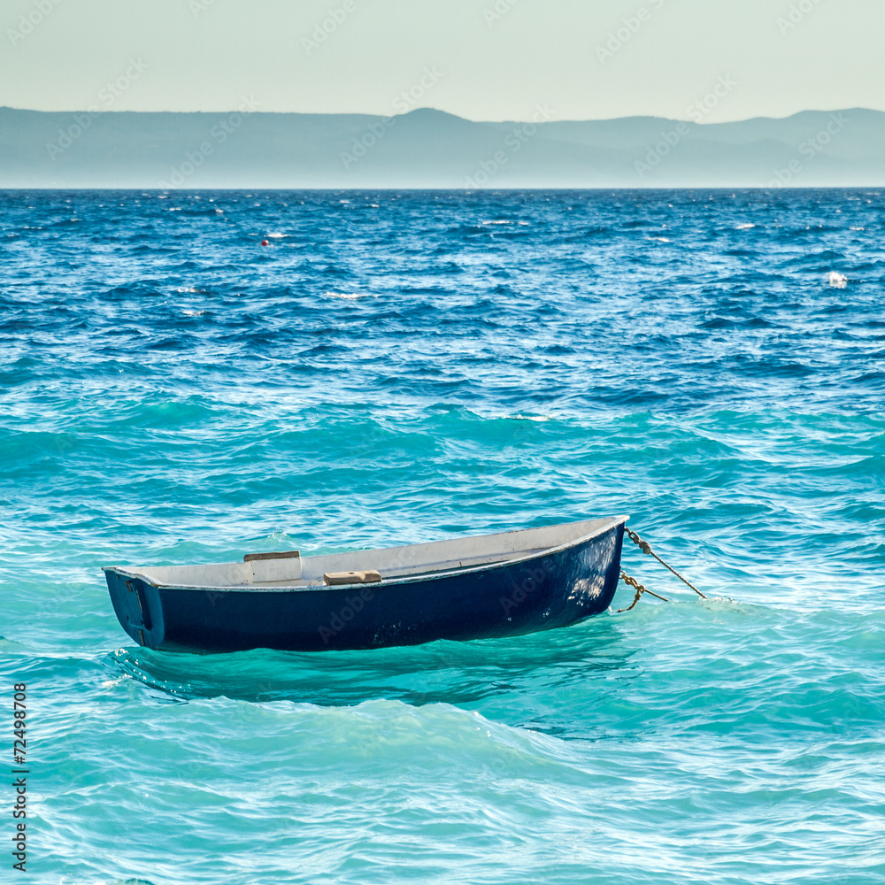 little blue boat is seesawing on waves in mediterrean little blue boat is seesawing on waves in mediterrean