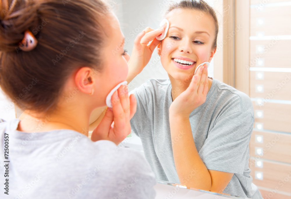 Beauty girl cleaning her face with cotton pad at home Beauty girl cleaning her face with cotton pad at home