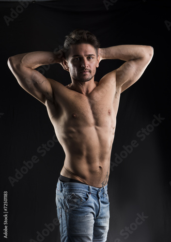 Handsome muscular shirtless young man with hands behind head