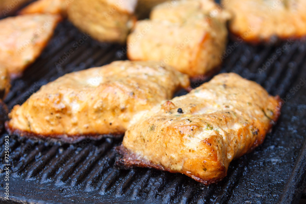 Salmon grilling on cast iron grill. Out of focus background.