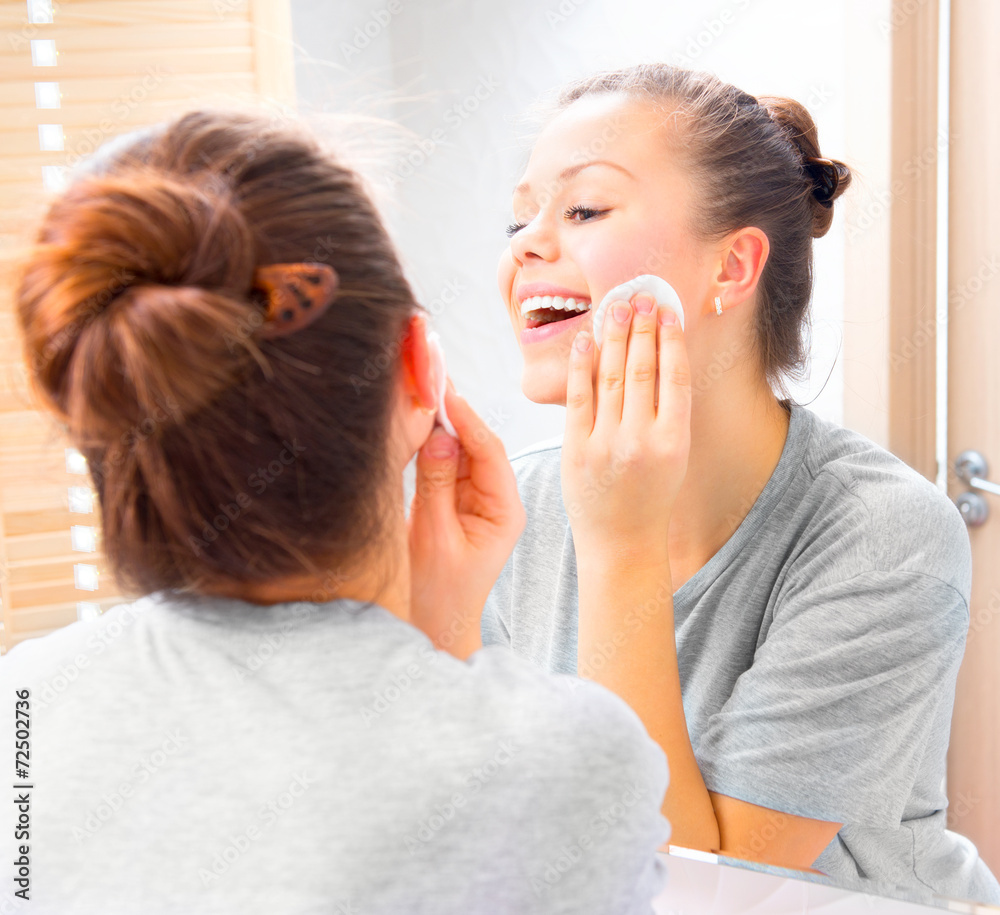 Beauty girl cleaning her face with cotton pad at home Beauty girl cleaning her face with cotton pad at home