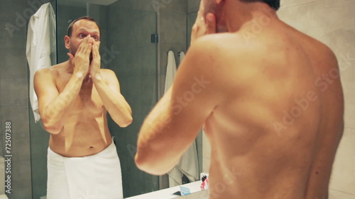 Man spread cream on his face in the bathroom after shower