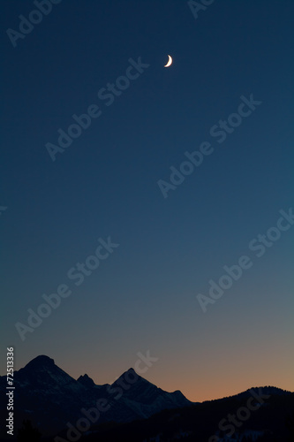 moon and mountain silhouettes over dark sky