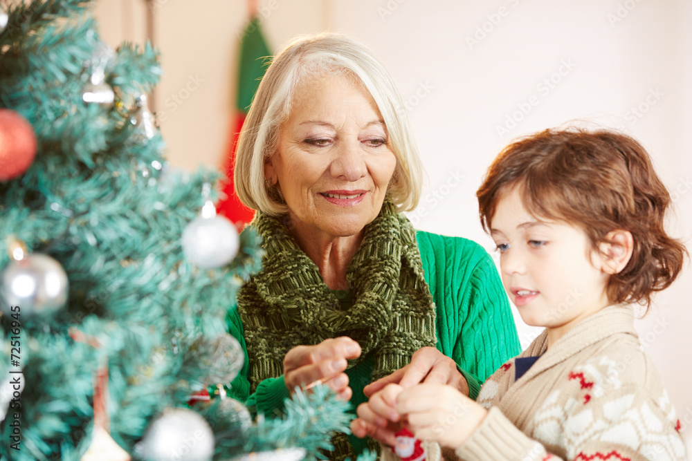 Enkel schmückt Weihnachtsbaum mit Großmutter zu Weihnachten Enkel schmückt Weihnachtsbaum mit Großmutter zu Weihnachten