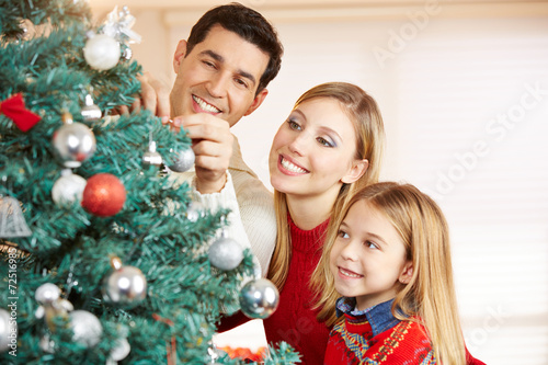 Familie schmückt Weihnachtsbaum zu Weihnachten