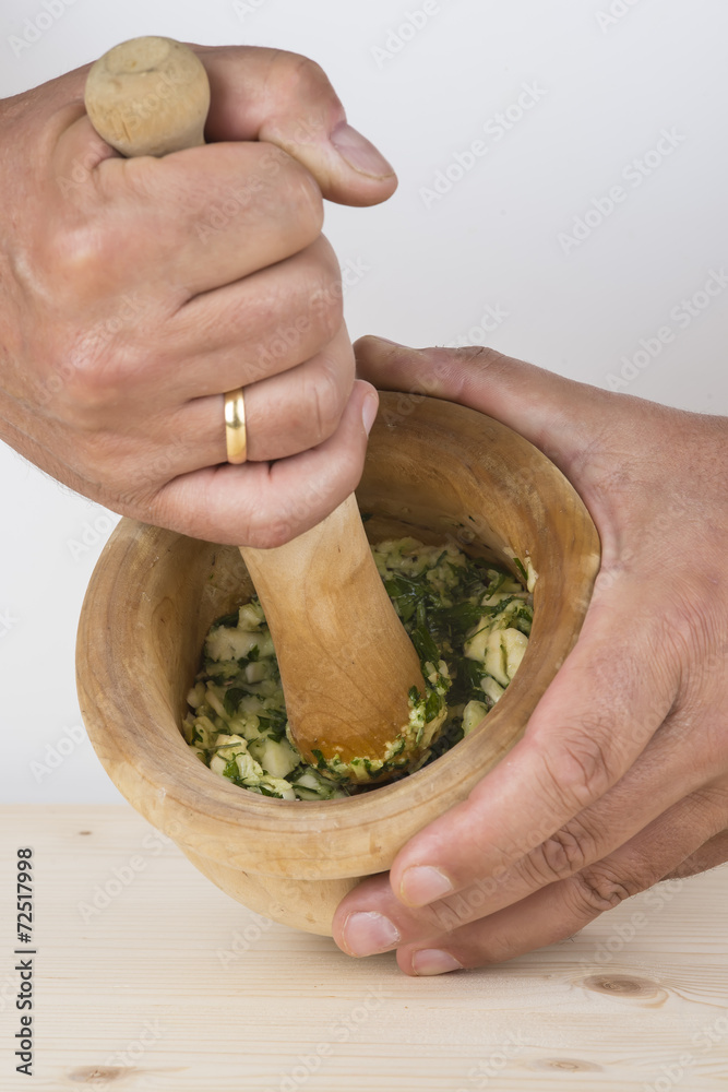 Cocinero preparando un majado de ajo y perejil en el mortero