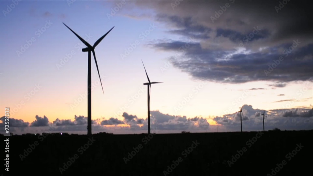 Wind turbines at sunset with clouds advancing Wind turbines at sunset with clouds advancing