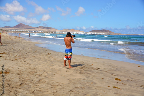 hombre caminando por la playa de famara en lanzarote