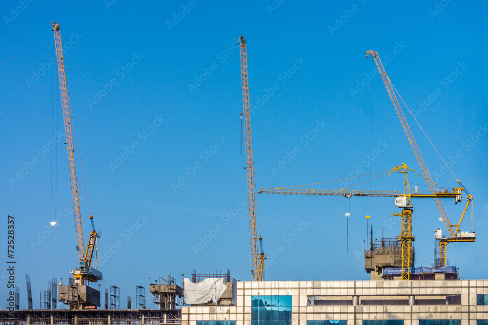 Cranes are working on the top of construction building