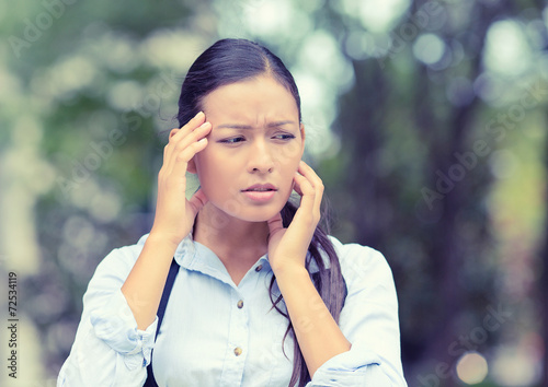 unhappy woman stressed having headache outside park background