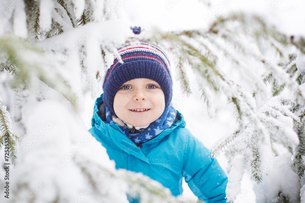 Little toddler boy having fun with snow outdoors on beautiful wi