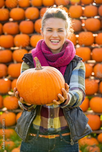 Closeup on smiling young woman holding pumpkin