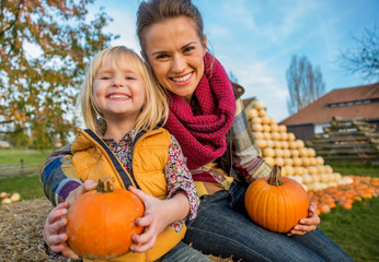 Portrait of smiling mother and child sitting on haystack with pu