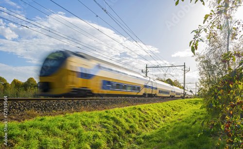 Passenger train moving at high speed in sunlight