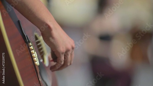 Playing on a brown guitar at daytime on the street