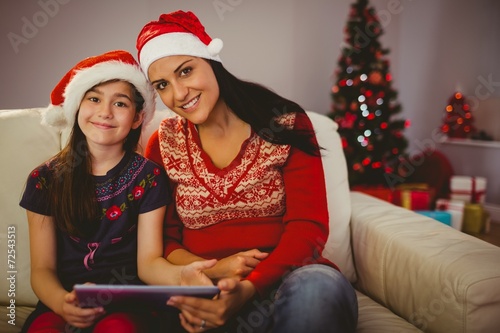 Festive mother and daughter using tablet