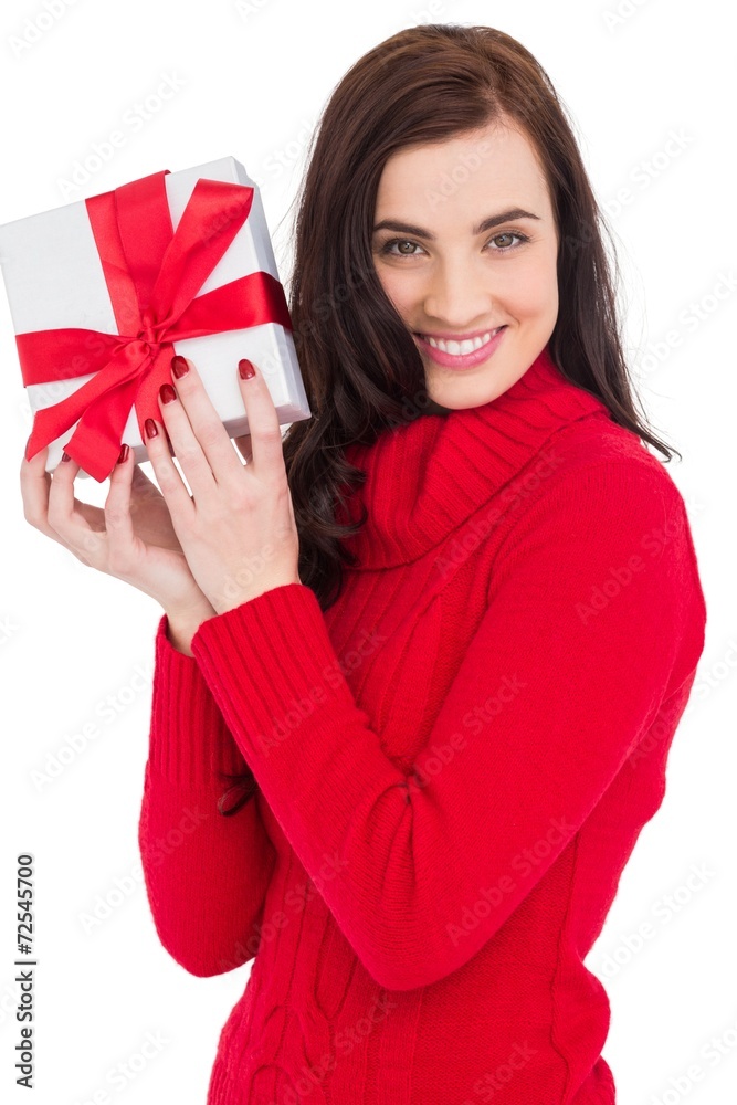 Smiling brunette in red jumper hat showing a gift Smiling brunette in red jumper hat showing a gift