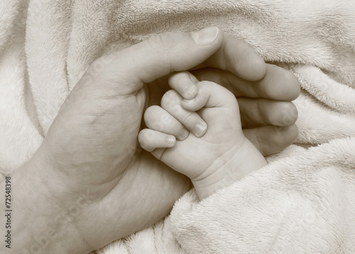 Father hold baby hand in the palm