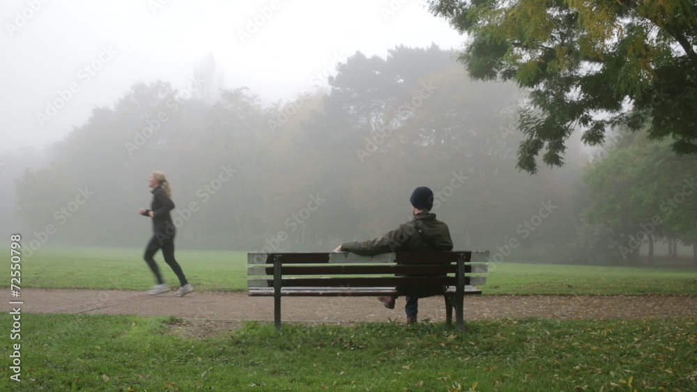 Man sitting on park bench on rainy day Man sitting on park bench on rainy day