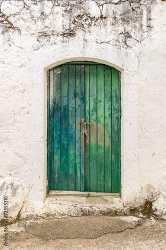 Old green timber door in the scuffed wall © artistique7