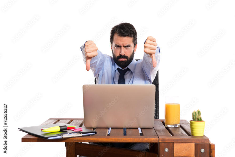 Businessman in his office doing a bad signal Businessman in his office doing a bad signal