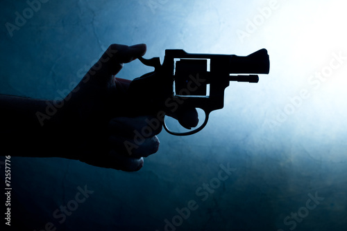Silhouette of a mans hand with a handgun photo