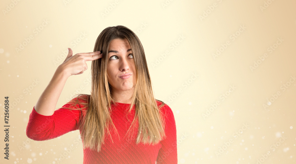 Young girl making suicide gesture over ocher background Young girl making suicide gesture over ocher background