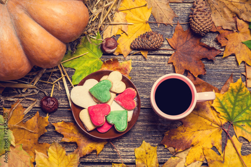 Cup of coffee and heart shape cookies on autumn background.