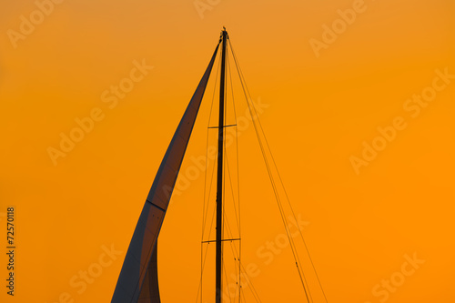 close up of a sail silhouette under an orange sky at sunset