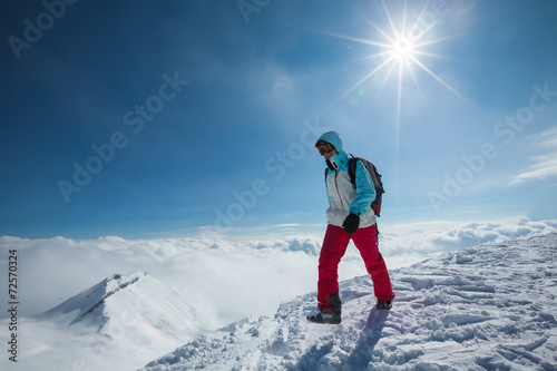 Hiker posing at top of snowy mountain during sunny day