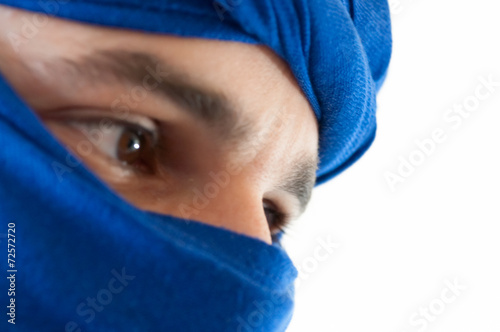 Close up of man wearing a blue keffiyeh against white background