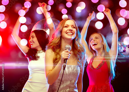 three smiling women dancing and singing karaoke
