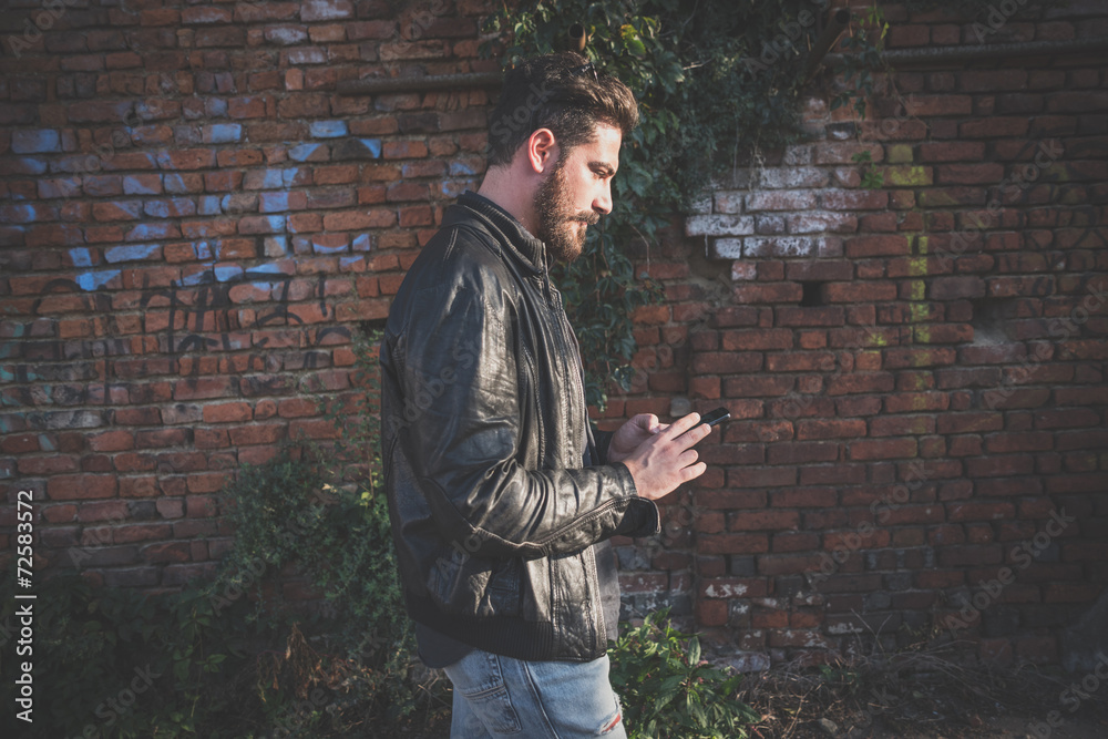 Side view of young man using smartphone while walking outdoors