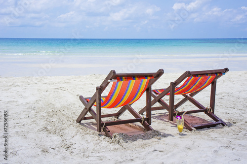 Two beach chairs on the white sand beach before blue sea © MarinadeArt