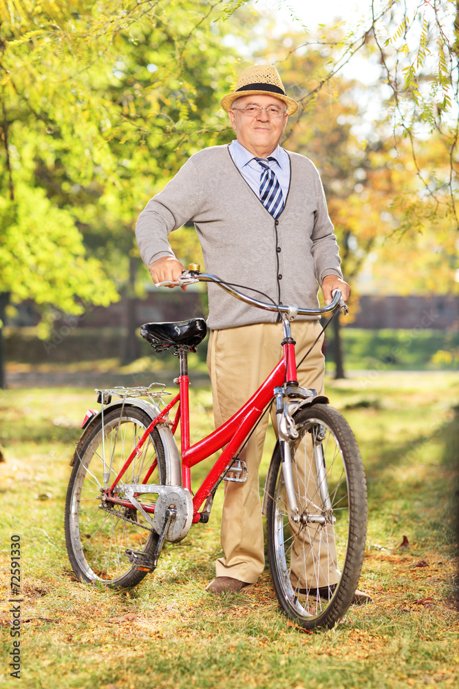 Senior gentleman pushing a bicycle in a park