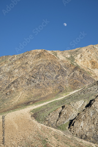 Moon over dirt mountain road