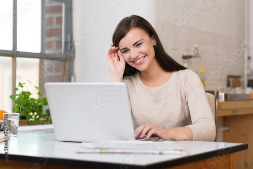 lachende junge frau schaut auf ihren laptop © contrastwerkstatt