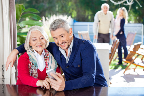 Smiling Grandson And Grandmother Using Smartphone