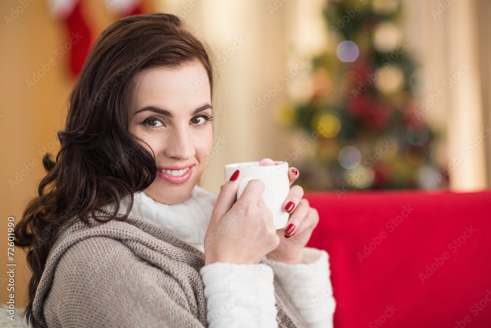 Smiling brunette holding a mug of hot chocolate at christmas Smiling brunette holding a mug of hot chocolate at christmas