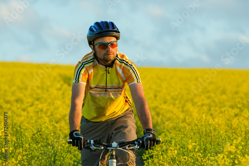 Mtb biker is cycling in yellow rapeseed field